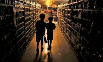  ?? KENT PORTER/ THE PRESS DEMOCRAT VIA AP ?? Elijah Carter, 11, left, and Robert Haralson, 12, help shop for their parents in 2019 in a darkened supermarke­t during a blackout in the Rincon Valley community in Santa Rosa, Calif.