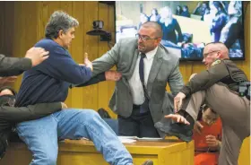  ?? Cory Morse / Grand Rapids Press ?? Randall Margraves (left) lunges at Larry Nassar (bottom right, in red) in the courthouse in Charlotte, Mich. Nassar abused Margraves’ three daughters.