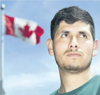  ?? GRAHAM HUGHES/THE CANADIAN PRESS ?? A Canadian flag flaps in the wind behind migrant worker Henry Aguirre of Guatemala during a demonstrat­ion in Montreal on July 23. Activists and migrant workers say Canada’s Temporary Foreign Worker program doesn’t adequately protect the rights of...