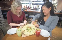  ?? PHOTOS BY DAVID WALLACE/THE REPUBLIC ?? Melissa Yeager, left, and Lauren Saria, sample the Cheese Crisp at Blanco Tacos in Terminal 4.