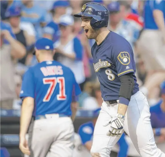  ??  ?? The Cubs’ Wade Davis exits while the Brewers’ Ryan Braun rejoices after Travis Shaw hit a two- run, game- winning homer against the Cubs in the 10th inning. | JEFFREY PHELPS/ AP