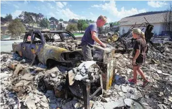  ??  ?? Saving what they can Bill Reed goes through the toolkit in what had been his garage as his daughter Erin searches through the rubble. Reed’s home was among those destroyed by the wildfire in Washington.