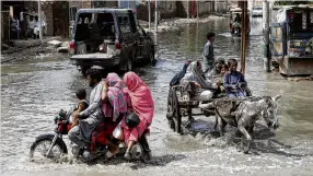  ?? PHOTO: REUTERS ?? Struggling on . . . People make their way through a flooded street in Jacobabad, Pakistan.