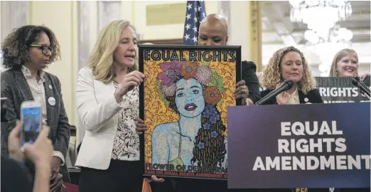  ?? DREW ANGERER/GETTY IMAGES ?? From left, Rep. Abigail Spanberger, D-Va., shows artwork to Rep. Ayanna Pressley, D-Mass., at a news conference to announce a joint resolution to affirm the ratificati­on of the Equal Rights Amendment on Capitol Hill on Jan. 31.