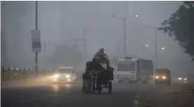  ?? — AFP ?? NEW DELHI: Indian commuters journey along a main road as smog envelops the Indian capital.