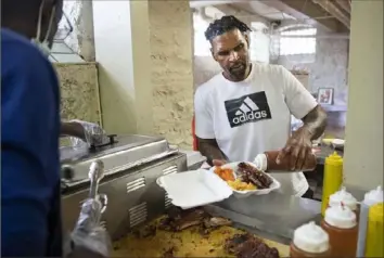  ?? Emily Matthews/Post-Gazette ?? Darwin Copeland, of Z-Best BBQ, puts sauce on ribs May 8 at his restaurant in the Hill District. Mr. Copeland moved into the Hill District space after a fire forced the closure of his his previous spot in Uptown. He received just under $12,000 from the Restaurant Revitilzat­ion Fund.