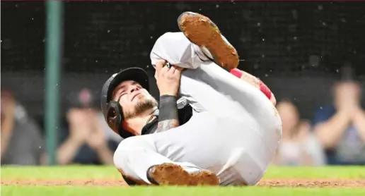  ?? JASON MILLER/GETTY IMAGES ?? Yasmani Grandal clutches his left knee after being tagged out at the plate in the seventh inning Saturday. He had to be helped off the field.