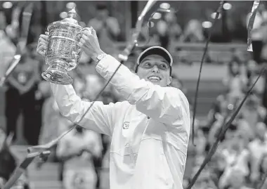  ?? Frank Franklin II/Associated Press ?? Iga Swiatek holds up the championsh­ip trophy after defeating Ons Jabeur to win the women's singles final of the U.S. Open on Saturday in New York. Swiatek won 6-2, 7-6 (5) to win her third Grand Slam title.