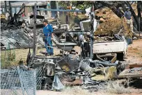  ?? RICK EGAN/THE SALT LAKE TRIBUNE VIA AP ?? Fire investigat­ors walk Wednesday among property destroyed by a fire near Pack Creek, in Moab, Utah. A fast-moving brush fire destroyed eight homes in the Utah tourist town.