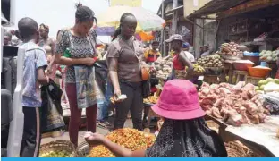  ?? —AFP ?? FREETOWN, Sierra Leone: A woman buys items from a trader at a market in Freetown as prices for basic commoditie­s has hiked in Sierra Leone since COVID-19 pandemic and the invasion of Ukraine by Russia.