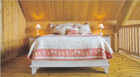  ??  ?? The cabin’s 20-by-30-foot mezzanine is occupied by a queen-size bed. Its country-style bedspread and matching pillows make the ensemble pop against the natural wood.