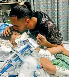  ?? AP ?? Ali Hassan kisses his dying 2-yearold son Abdullah in a Sacramento hospital. The boy’s Yemeni mother, blocked by the Trump administra­tion’s travel ban, has won her fight for a waiver that would allow her to travel to see her son.