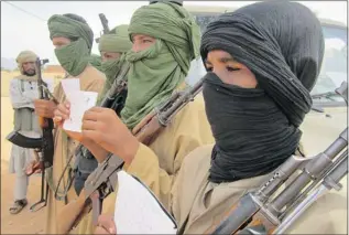  ?? BABA AHMED/THE Associated Press ?? Young fighters, including 13-year-old Abdullahi, right, and 14-year-old Hamadi, second right, display their Quranic studies notes for a journalist as their Islamist commanders look on, in Douentza, Mali.