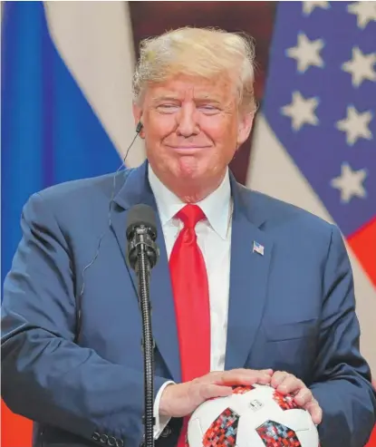  ?? YURI KADOBNOV/AFP/GETTY IMAGES ?? President Donald Trump holds a World Cup ball given to him by Russian President Vladimir Putin.