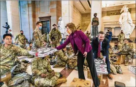  ?? MANUEL BALCE CENETA / AP ?? Rep. Vicky Hartzler, R-Mo., and Rep. Michael Waltz, R-Fla., hand pizzas to members of the National Guard gathered at the Capitol Visitor Center, Wednesday, as the House continues with its vote to impeach President Donald Trump.