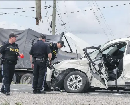  ?? JASON KRYK ?? Ontario Provincial Police collision reconstruc­tion specialist­s examine the scene of a fatal crash involving a transport truck and a Chevrolet Equinox on Wednesday near Comber at Highway 77 and Lakeshore Road 310. One driver was killed and the other...