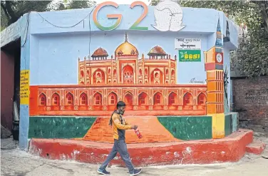  ?? AFP ?? A man walks past a wall mural of Humayun’s tomb under the logo of G20 summit, in New Delhi yesterday. India will host the G20 summit in September 2023 and hold several meetings during its presidency.