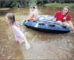  ?? AP PHOTO ?? Crimson Peters, 7, from left, Tracy Neilsen, 13, and Macee Nelson, 15, ride in an inner tube down a flooded street after hurricane Nate on Sunday in Coden, Alabama.