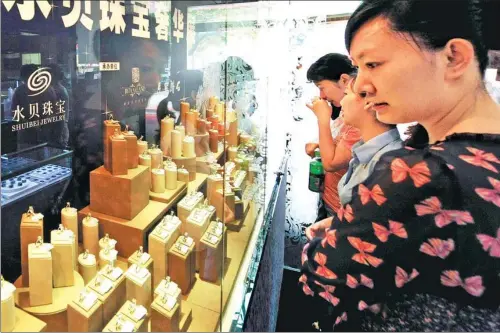  ?? CHEN YEHUA / XINHUA ?? Customers examine jewelry in Shuibei village, Guangdong province, once a leading production center in China.