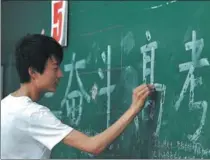  ?? LU QIJIAN / VCG ?? Above left: A student writes a slogan to cheer up his peers in Fuyang city, Anhui province.