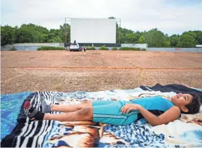  ?? PHOTOS BY ARIEL COBBERT/THE COMMERCIAL APPEAL ?? Lamarcus Blades stretches out on his blanket before a movie starts Friday at the Malco Summer Quartet Drive-in. The drive-in became the first movie theater to reopen during the pandemic.