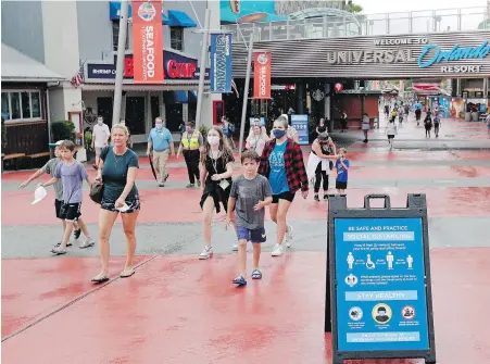  ??  ?? Visitors to newly reopened Universal Orlando Resort tare reminded about social distancing and other protocols.