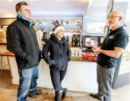  ?? JOHN MAHONEY ?? Owner David Epstein, right, talks with regular customers Frederic Searle and Catherine Blais at Studio 77 in Pointe Claire Village on Monday. Epstein says the area has a parking problem.