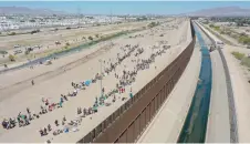  ?? — AFP file photos ?? An aerial image shows migrants waiting along the border wall to surrender to US Customs and Border Protection (CBP) border patrol agents for immigratio­n and asylum claim processing after crossing the Rio Grande River into the US, on the US-Mexico border in El Paso, Texas.