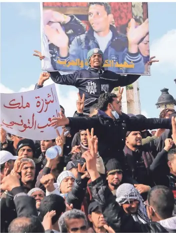  ?? FOTO: SALAH HABIBI/AP ?? In der tunesische­n Hauptstadt Tunis protestier­en im Januar 2011 Demonstran­ten gegen die Regierung und zeigen ein Bild des Gemüsehänd­lers Mohammed Bouazizi, der sich selbst angezündet hatte.