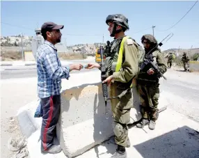  ??  ?? A SOLDIER SEARCHES a Palestinia­n at a checkpoint south of Hebron last month.
