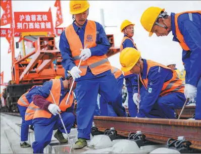 ?? WU HUAIQIU / FOR CHINA DAILY ?? Employees of China Railway No 4 Engineerin­g Group Co Ltd lay tracks on the Wuhan-Yichang section of the Shanghai-ChongqingC­hengdu High-speed Railway in Jingmen, Hubei province.