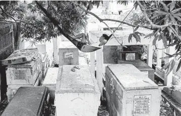  ?? AARON FAVILA/AP ?? A cemetery to himself: A man relaxes on a hammockWed­nesday inside a cemetery in Manila, Philippine­s. To help curb the spread of the coronaviru­s, the government has ordered all cemeteries, memorial parks and columbaria to be closed for a week starting Thursday to prevent gatherings for the traditiona­lly crowded observance­s of All Saints Day.