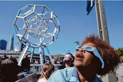  ?? Eric Risberg/Associated Press ?? Shirley Moore, wearing protective glasses, watches the solar eclipse Monday outside the Explorator­ium in San Francisco.