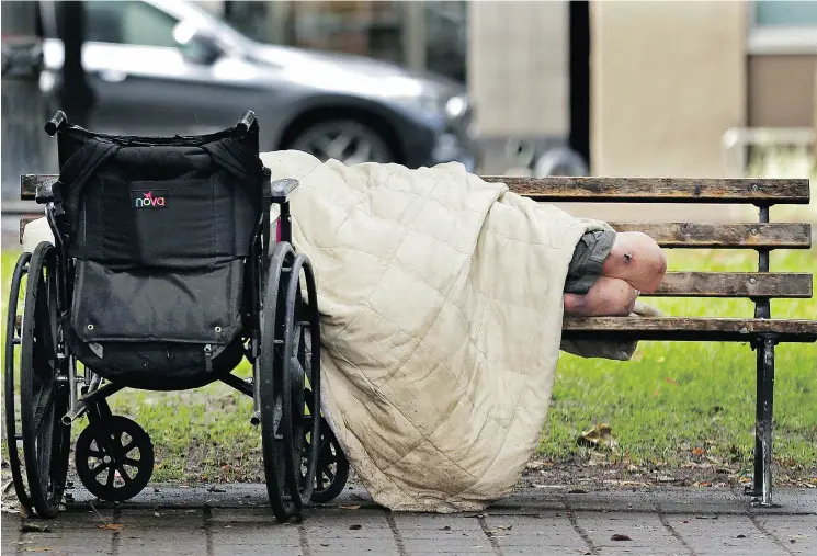  ?? TED S. WARREN / THE ASSOCIATED PRESS ?? A person sleeps next to a wheelchair on a park bench in downtown Portland, Ore., not far from the city’s trendy Pearl District.