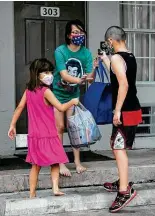  ??  ?? Chloe and Donna, with their sibling Jacob Reyna, 10, carry the food, which was delivered by Kelly Delgado and her son, Daughnavin Delgado (not pictured).