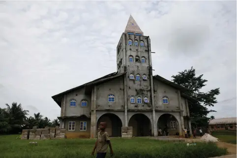  ?? (Reuters) ?? A BOY walk past the Apostolic church in Bodo, Nigeria.