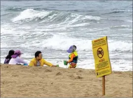  ?? Allen J. Schaben Los Angeles Times ?? BEACHGOERS play near a warning sign at Dockweiler State Beach on Thursday. Residents have complained of continuous foul odors, as well as rashes and nausea.