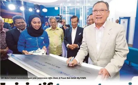  ??  ?? DR Mohd Zahidi menandatan­gani plak pelancaran Affin Bank di Pusat Beli-Belah MyTOWN.