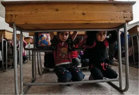  ?? SAMEER AL-DOUMY/AFP/GETTY IMAGES ?? Syrian schoolchil­dren crouch under their desks during lessons on how to protect themselves in case of bombardmen­t in a rebel-held area near Damascus.