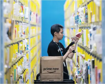  ?? JOSEPH NAIR / THE ASSOCIATED PRESS ?? A staff member scans a product at the newly opened Amazon Prime Now facility in Singapore on Thursday. The company is expanding into India and Australia, as well.