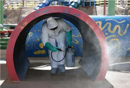 ?? Photograph: Ethan Miller/Getty Images ?? A Las Vegas maintenanc­e worker disinfects playground equipment.