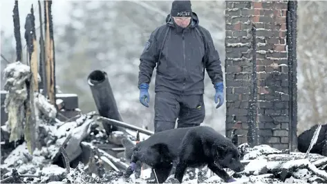  ?? ANDREW VAUGHAN/ THE CANADIAN PRESS ?? An RCMP officers and a human remains detection dog search the scene of a house destroyed in a weekend fire in Pubnico Head, N. S. on Monday. The fire left four people dead, including at least two children, according to a relative.