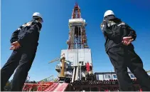  ?? REUTERS ?? WORKERS look at a drilling rig in Nefteyugan­sk, Russia, Aug. 4, 2016.