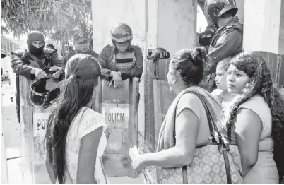  ?? — Gambar ?? AHLI keluarga banduan berhimpun di hadapan polis pencegah rusuhan di luar penjara Las Cruces di Acapulco, negeri Guerrero selepas rusuhan ganas di antara banduan menyebabka­n 28 maut dan tiga lagi cedera kelmarin.