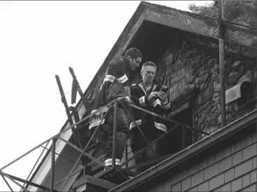  ??  ?? Investigat­ors probe the charred roof of Rockland Manor after a fire in June displaced 18 residents.