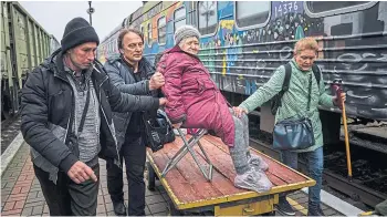  ?? ?? Relatives of Elizaveta, 94, transport her to the evacuation train in Kherson.