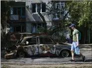  ?? ?? A man carries water in front of an apartment building damaged in an overnight missile strike, in Sloviansk, Ukraine, Tuesday, May 31, 2022. In towns and cities near the fighting in eastern Ukraine, artillery and missile strikes have downed power lines and punched through water pipes, leaving many without electricit­y or water as repair crews race to repair the damage.