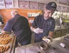  ?? STEPHAN SAVOIA, AP ?? Sal O’Brien preps a hot wiener with all the fixings or “all the way” at Olneyville New York System in Providence.