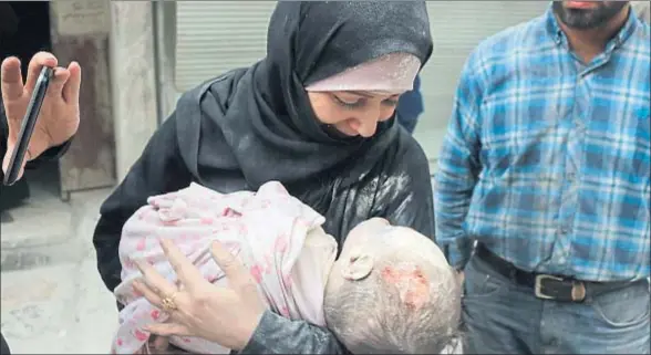 ?? THAER MOHAMMED / AFP ?? Una mujer de Alepo sostiene el cuerpo de su hijo, encontrado bajo las ruinas de su casa tras un bombardeo