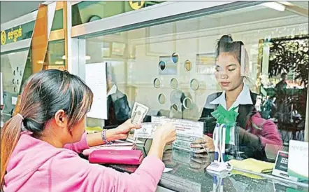  ?? HONG MENEA ?? A woman receives money from a finance officer at a Phnom Penh branch of Prasac Microfinan­ce Institutio­n.